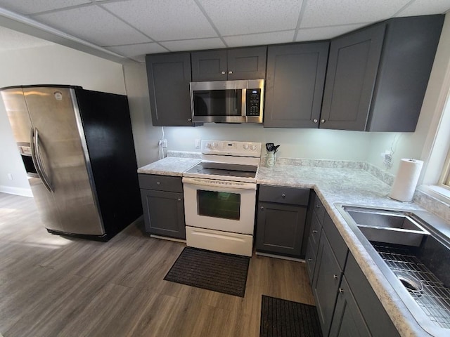 kitchen with dark wood-type flooring, gray cabinets, stainless steel appliances, light countertops, and a sink