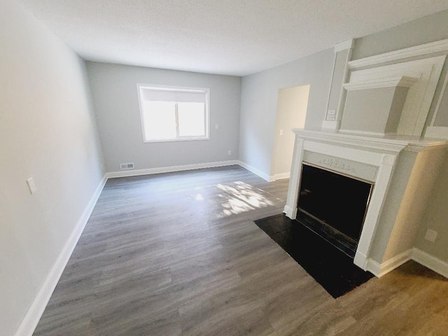 unfurnished living room with dark wood-style floors, visible vents, a premium fireplace, and baseboards