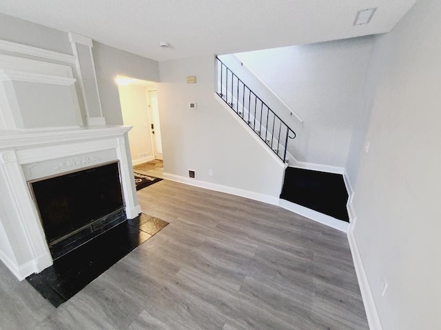 living room with baseboards, a fireplace with flush hearth, stairway, and wood finished floors