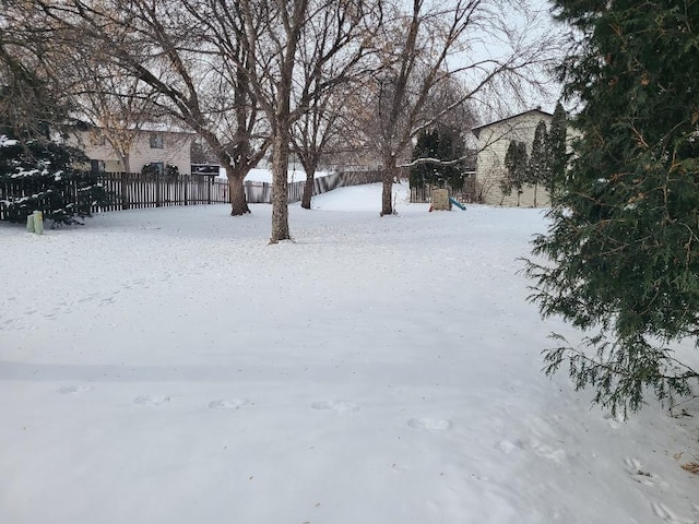 yard covered in snow with a playground and fence