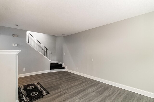unfurnished living room featuring baseboards, wood finished floors, and stairway