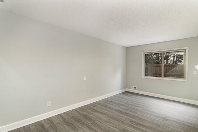 unfurnished room with baseboards, visible vents, a textured ceiling, and dark wood-type flooring