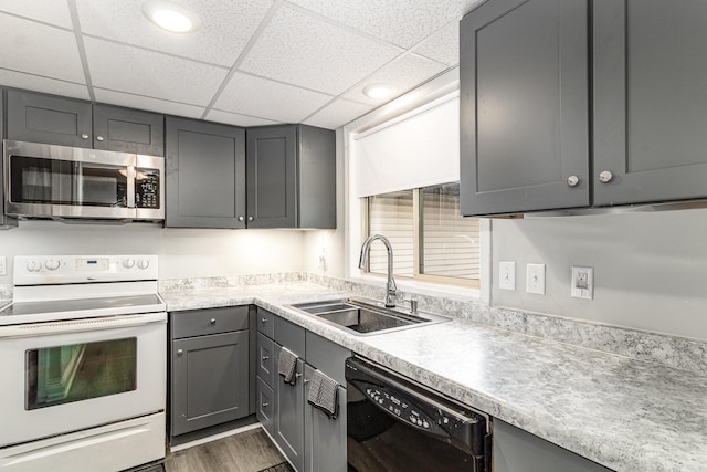 kitchen with white electric range, gray cabinets, stainless steel microwave, a sink, and dishwasher