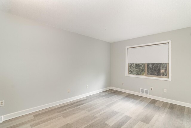 unfurnished room with baseboards, light wood-style flooring, and visible vents