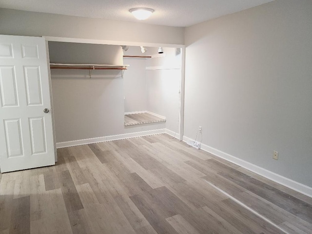 unfurnished bedroom featuring baseboards, a closet, and wood finished floors