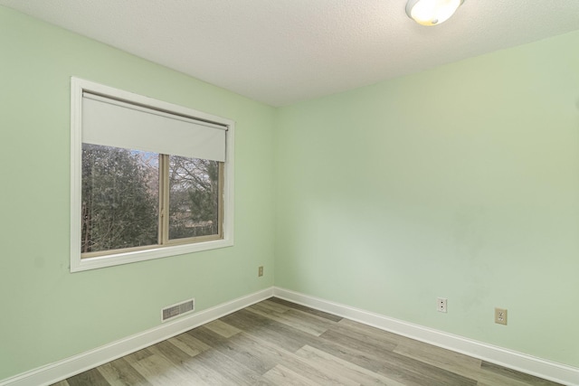 empty room featuring baseboards, visible vents, and wood finished floors
