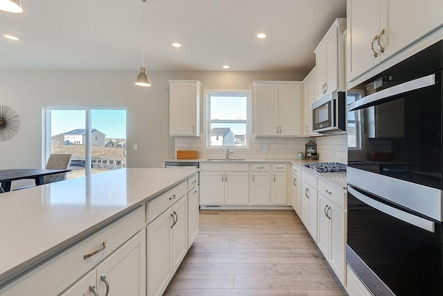 kitchen featuring decorative light fixtures, backsplash, sink, appliances with stainless steel finishes, and white cabinets