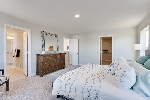 bedroom featuring ensuite bathroom, a closet, a spacious closet, and light carpet