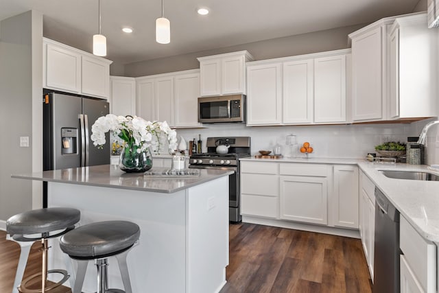 kitchen with sink, white cabinetry, hanging light fixtures, stainless steel appliances, and dark hardwood / wood-style flooring