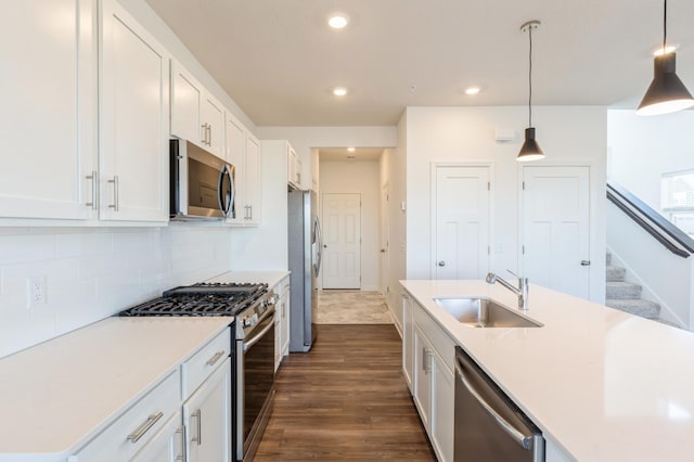 kitchen featuring stainless steel appliances, pendant lighting, white cabinetry, and sink