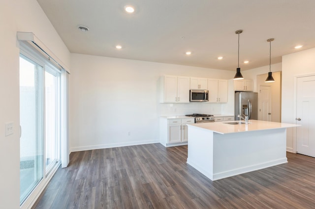 kitchen featuring decorative light fixtures, white cabinetry, dark hardwood / wood-style flooring, stainless steel appliances, and a center island with sink