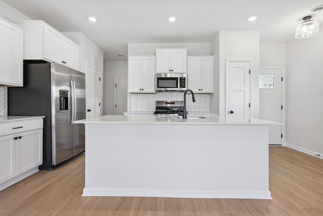 kitchen with sink, stainless steel appliances, a center island with sink, and decorative backsplash