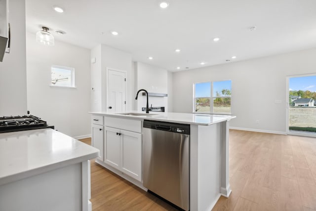 kitchen featuring stainless steel dishwasher, sink, white cabinetry, a wealth of natural light, and a kitchen island with sink