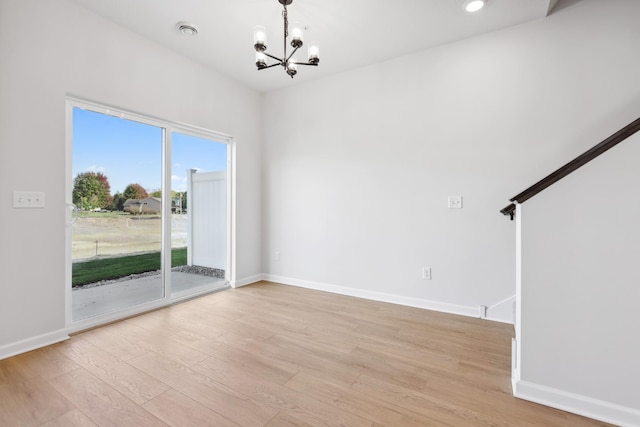 unfurnished room with a notable chandelier and light wood-type flooring