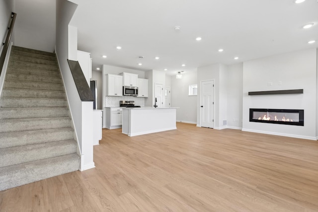 unfurnished living room with sink and light hardwood / wood-style flooring