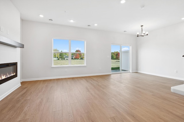 unfurnished living room with light hardwood / wood-style flooring and an inviting chandelier