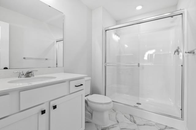 bathroom featuring vanity, a shower with shower door, and toilet