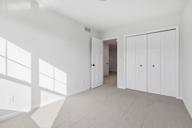 unfurnished bedroom featuring light colored carpet and a closet