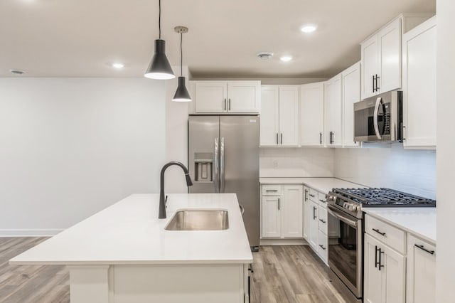 kitchen featuring hanging light fixtures, appliances with stainless steel finishes, white cabinetry, and a center island with sink