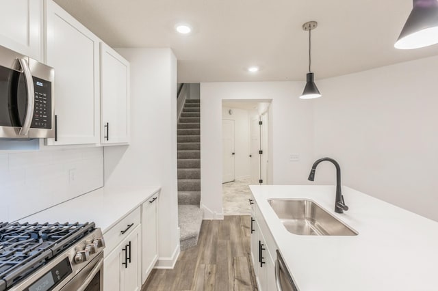 kitchen with appliances with stainless steel finishes, white cabinets, hanging light fixtures, and sink