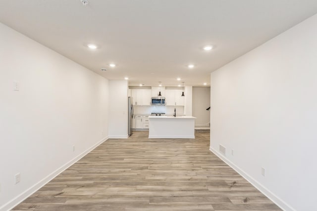 unfurnished living room with light wood-type flooring and sink