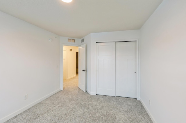 unfurnished bedroom featuring light colored carpet and a closet