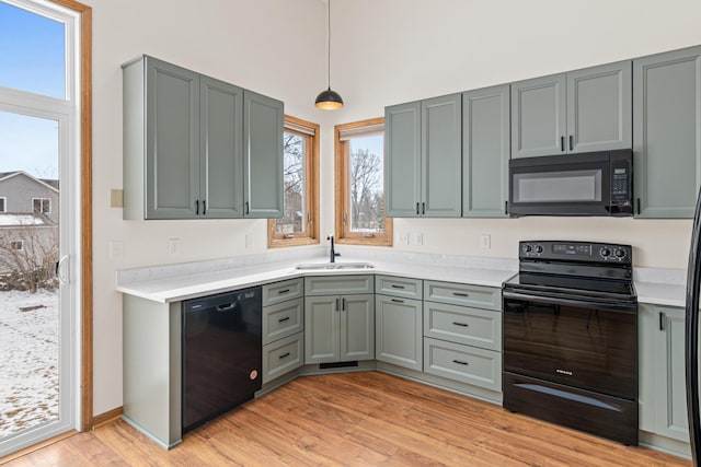 kitchen featuring light hardwood / wood-style flooring, sink, hanging light fixtures, and black appliances