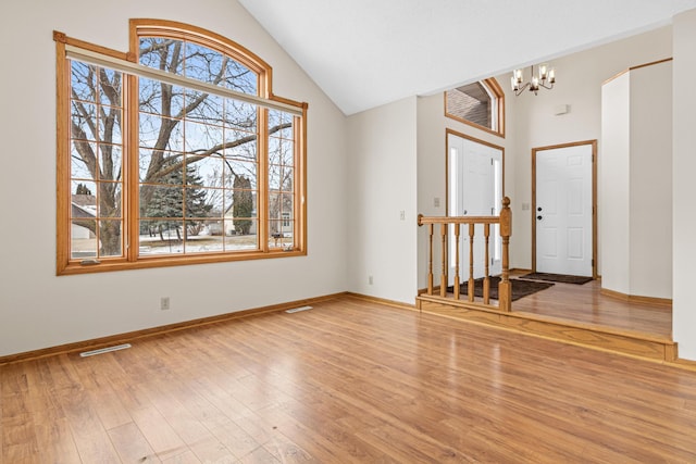 foyer with a notable chandelier, high vaulted ceiling, and light hardwood / wood-style flooring