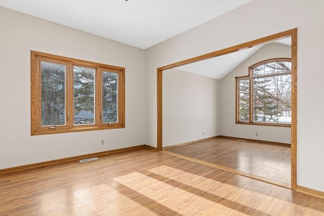 spare room featuring lofted ceiling and light hardwood / wood-style floors