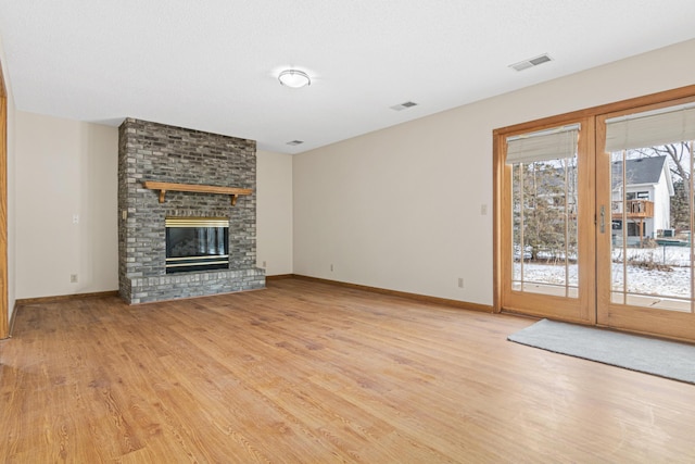 unfurnished living room with a brick fireplace and light wood-type flooring