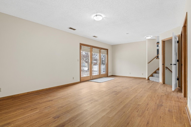 unfurnished room with french doors, light wood finished floors, visible vents, stairway, and baseboards