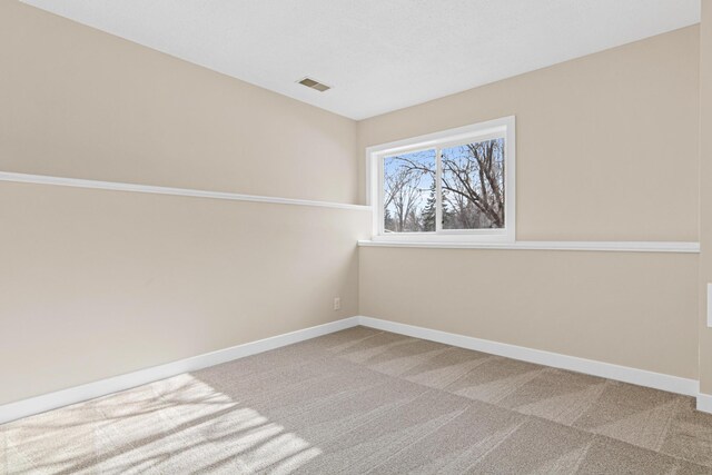 carpeted empty room featuring baseboards and visible vents