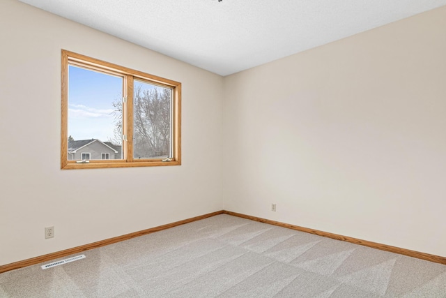 empty room with visible vents, light carpet, baseboards, and a textured ceiling