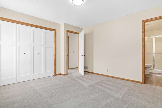 unfurnished bedroom featuring light colored carpet, ensuite bath, visible vents, and baseboards