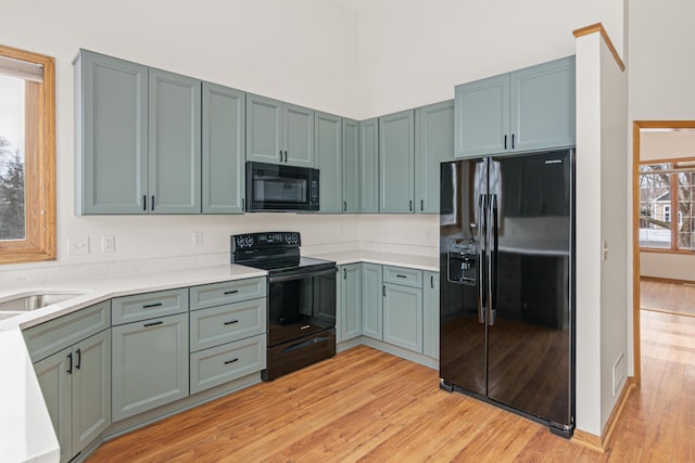 6462 Kingfisher Ct, Lino Lakes, MN 55014 - kitchen featuring black appliances, light wood-style flooring, light countertops, and a high ceiling