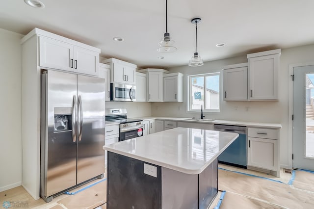 kitchen with pendant lighting, sink, appliances with stainless steel finishes, white cabinets, and a kitchen island