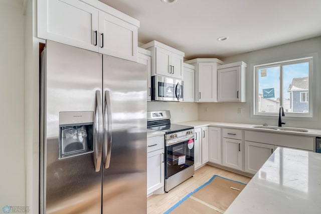 kitchen featuring light stone counters, appliances with stainless steel finishes, sink, and white cabinets