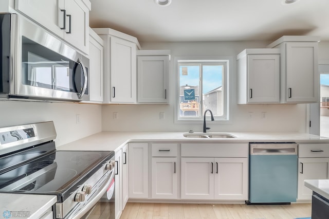 kitchen featuring white cabinetry, sink, light wood-type flooring, and appliances with stainless steel finishes