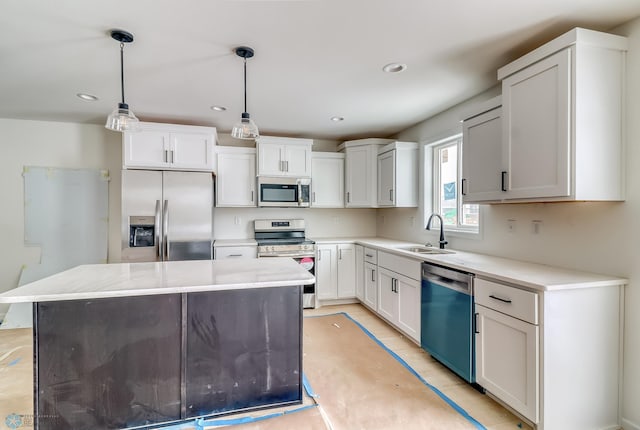 kitchen featuring sink, white cabinetry, stainless steel appliances, a center island, and decorative light fixtures