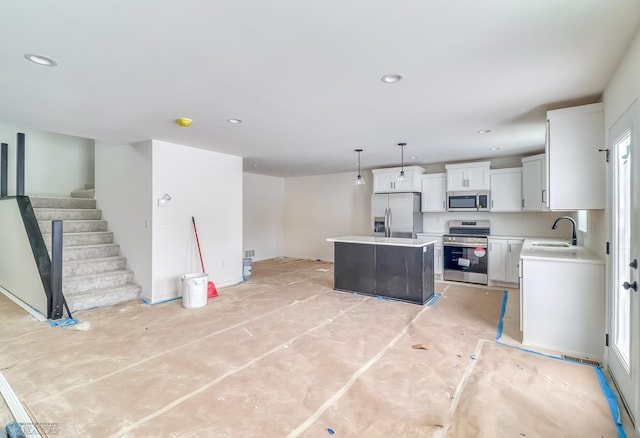 kitchen featuring sink, white cabinetry, hanging light fixtures, appliances with stainless steel finishes, and a kitchen island