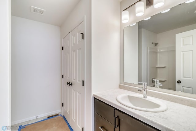 bathroom featuring tile patterned flooring, vanity, and walk in shower