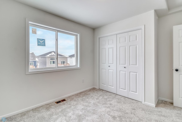 unfurnished bedroom featuring light colored carpet and a closet