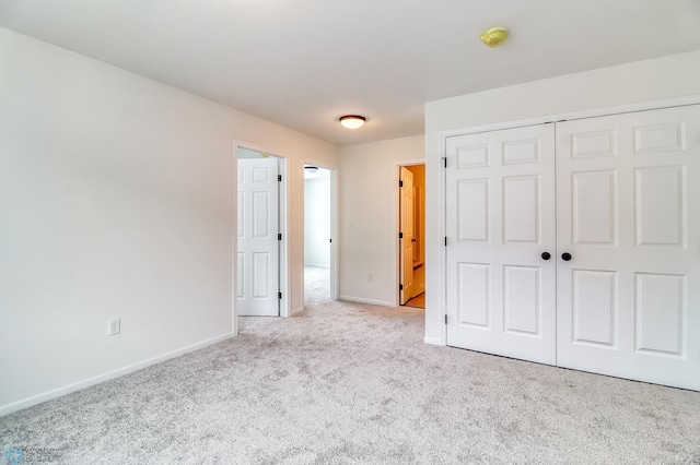 unfurnished bedroom with light colored carpet and a closet