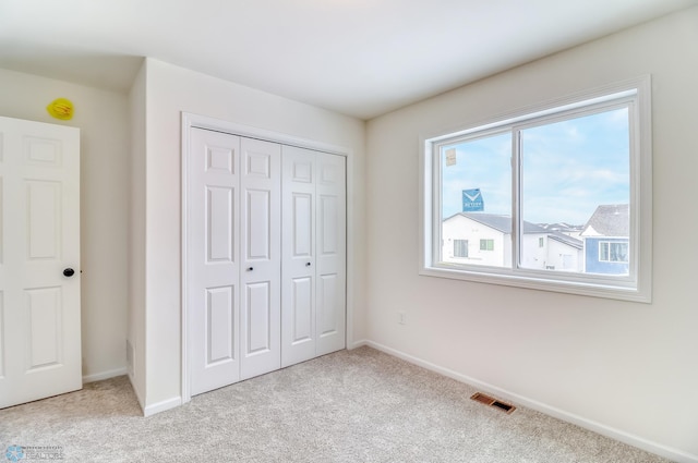 unfurnished bedroom featuring light colored carpet and a closet