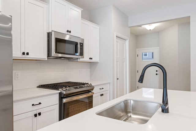 kitchen with white cabinetry, appliances with stainless steel finishes, sink, and decorative backsplash