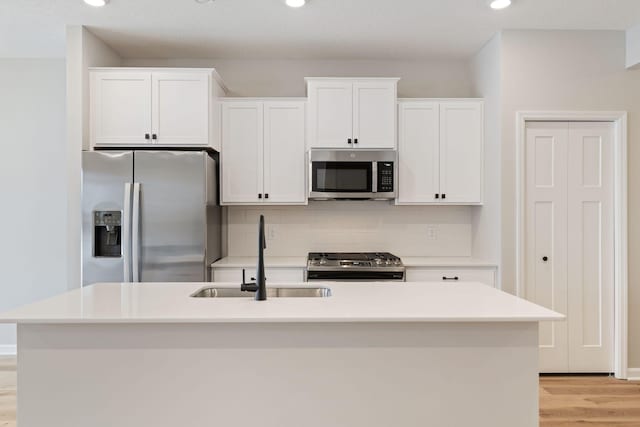 kitchen featuring appliances with stainless steel finishes, sink, a center island with sink, and white cabinets