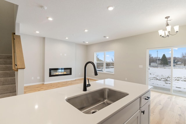 kitchen featuring sink, white cabinetry, a chandelier, pendant lighting, and light hardwood / wood-style floors