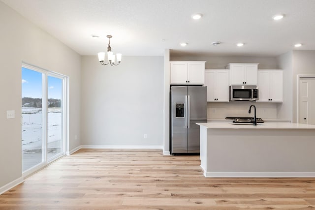 kitchen with white cabinetry, backsplash, hanging light fixtures, stainless steel appliances, and light wood-type flooring