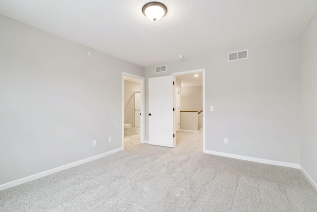 unfurnished bedroom with a walk in closet, light carpet, and a textured ceiling