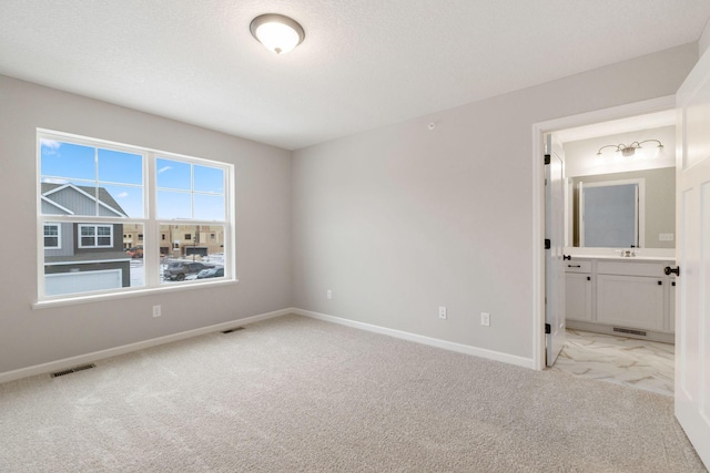 unfurnished bedroom with sink, connected bathroom, and light colored carpet